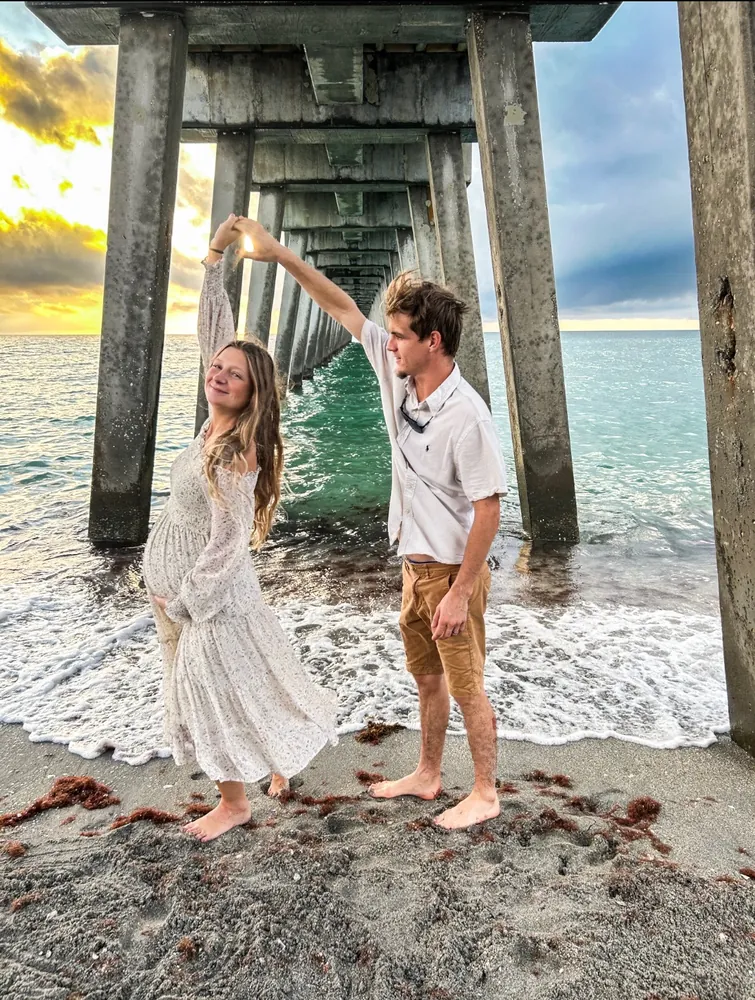 Couple dancing under the pier at sunset