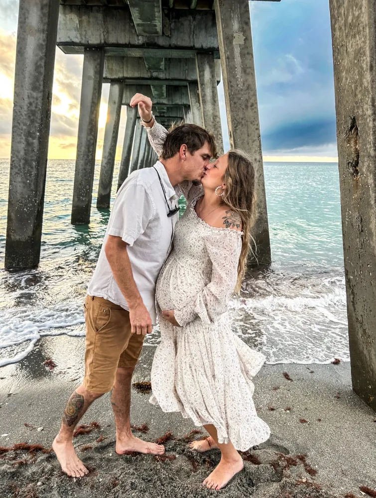 Couple kissing under the pier at golden hour